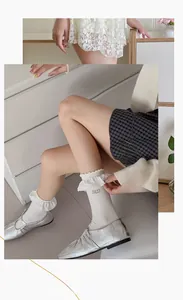 Gros plan sur des chaussettes blanches Lolita avec bords à volants et broderie M.D.