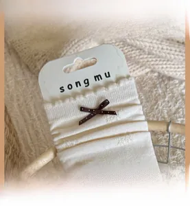 Close-up of white ribbed socks featuring a wavy edge and a brown polka dot bow detail