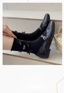 Détail de chaussettes noires tricotées avec nœud en soie et broderie argentée
