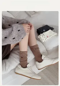 Détail de chaussettes mi-mollet marron café avec pois blancs et broderie douce