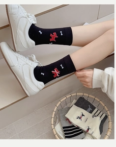 Detail of black cotton socks with red puppy pattern and pink 3D bow on a model