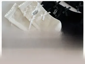 Gros plan de chaussettes en coton avec nœud décoratif et détails brodés de lettres MD