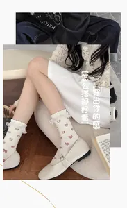 Close-up of white lace trim socks with red bow pattern and Mary Jane shoes