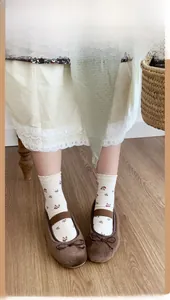 Detail of floral mid-calf socks paired with brown ballet flats on light wood floor