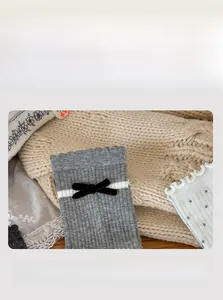 Détail des revers élastiques à volants sur chaussettes grises avec nœuds en velours noir