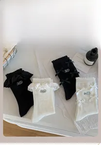 Gros plan de chaussettes mi-mollet noires et crème avec nœuds et bordure en dentelle