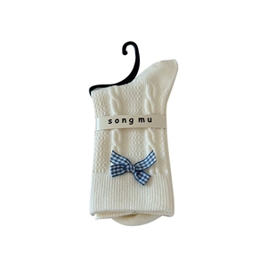 White knit crew socks with blue checkered bow and cable stitch pattern on white background