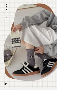 Detail of grey knitted mid-calf sock featuring ruffle edge and cute panda embroidery