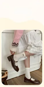 Detail of white lace crew socks with brown bows paired with vintage Mary Jane shoes