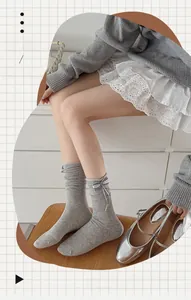 Detail of grey mid-calf socks with plaid bows paired with silver Mary Jane shoes