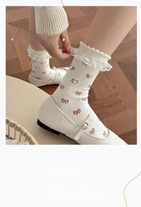 Detail of sweet white lace socks with red bows and pearls worn with Mary Jane shoes
