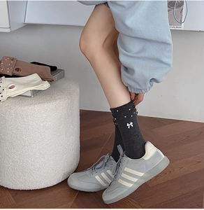 Détail de chaussettes en coton gris foncé à pois avec broderie nœud blanc