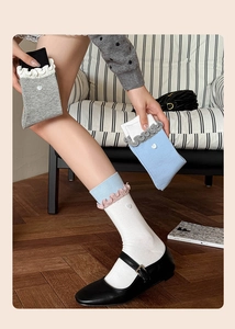 Detail of ruffled cuff socks with heart-shaped buttons shown in a cozy indoor setting