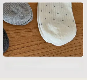 Détail de chaussettes grises à pois montrant la couture plate et la maille fine tricotée