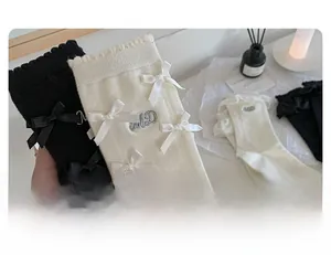 Détail de chaussettes mi-mollet Lolita avec nœuds satinés et bordure en dentelle