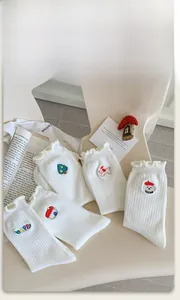 Detail of white cotton socks with lettuce edge cuffs and cute cartoon embroidery