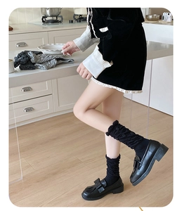 Detail of sweet ruffle cuffs on grey slouch socks paired with black bow loafers