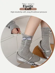 Detailed view of elastic ribbed cuff and decorative plaid bow on grey knit socks