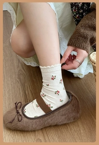 Detail of plush brown ballet flats with bow and floral knit socks on wooden floor