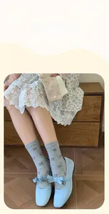 Close-up of cotton crew socks featuring side buttons and bow patterns in soft gray tones