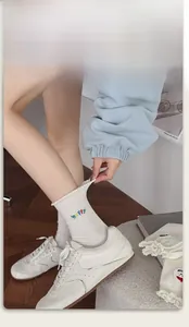 Close-up of elastic ribbed cuff and Happy embroidery on white cotton socks with lace trim