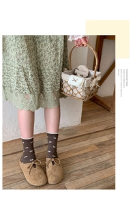 Close-up of brown floral crew socks with scalloped edges and tan suede mule shoes