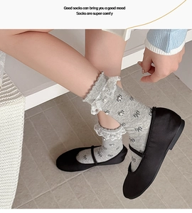 Grey mid-calf socks with white lace trim, pearls, and black bow patterns on feet