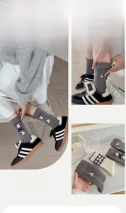 Detail of grey knitted mid-calf socks with cute cartoon dog embroidery and bow accents