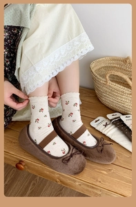 Detail of dark brown plush ballet flats with bow and floral embroidered crew socks