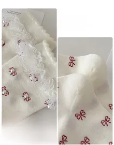 Detail of white lace knit socks with red bow embroidery and pearl beads accent
