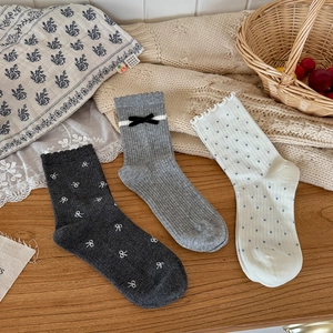 Trois paires de chaussettes grises et blanches à nœuds et pois sur un plateau en bois