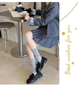 Detail of grey preppy style slouch socks with button accents and black bow loafers
