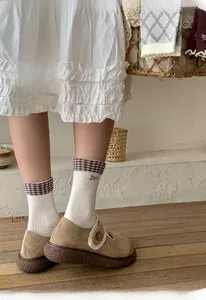 Close-up of cream cotton socks with burgundy checkered cuffs and purple bow embroidery