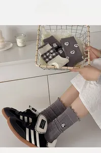 Close-up of cute cartoon dog embroidery and ruffled lettuce trim on gray crew socks