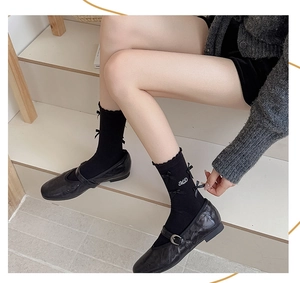 Gros plan détaillé de chaussettes Lolita noires avec nœuds et broderie de lettres MD