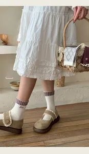 Detail of white cotton sock with retro plaid trim and delicate bow embroidery