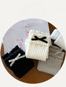 Detailed knit texture of ruffle trim socks with velvet bows in black, white, and grey
