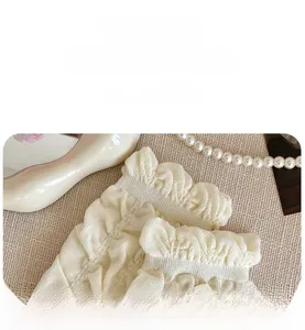 Detail of high-elastic knit texture and ruffle edge on white slouch socks with pearls