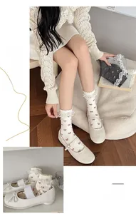 Close-up of white lace trim socks with red bow patterns and Mary Jane shoes