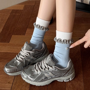Blue heart-button crew socks with ruffled cuffs paired with silver metallic retro sneakers
