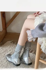 Détail de chaussettes grises à côtes avec nœud argenté et souliers Mary Jane