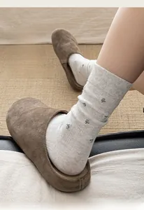 Détail de chaussettes à fleurs gris clair avec des pantoufles en daim marron foncé