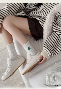 Detail of white cotton crew socks with colorful embroidery and ruffle trim with sneakers