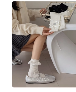 Gros plan de chaussettes blanches à volants avec nœuds et broderie de lettres MD