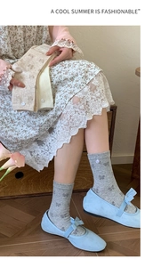 Detail of grey bow pattern socks with small white button accents and soft knit texture
