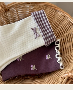 Detail of cotton crew socks with floral embroidery and bow accents in a wicker basket