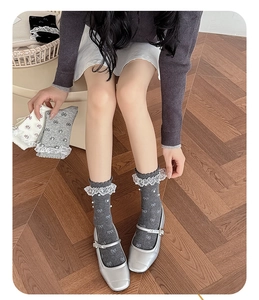 Detail of grey lace trim crew socks featuring white bow motifs and pearl embellishments