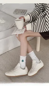 Detail of white cotton socks with green tree embroidery and ruffled cuff on model
