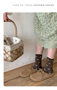 Detail of vintage brown floral cotton socks styled with lace dress and retro shoes