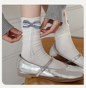 Detail of white knit crew socks with blue checkered bow and silver Mary Jane shoes